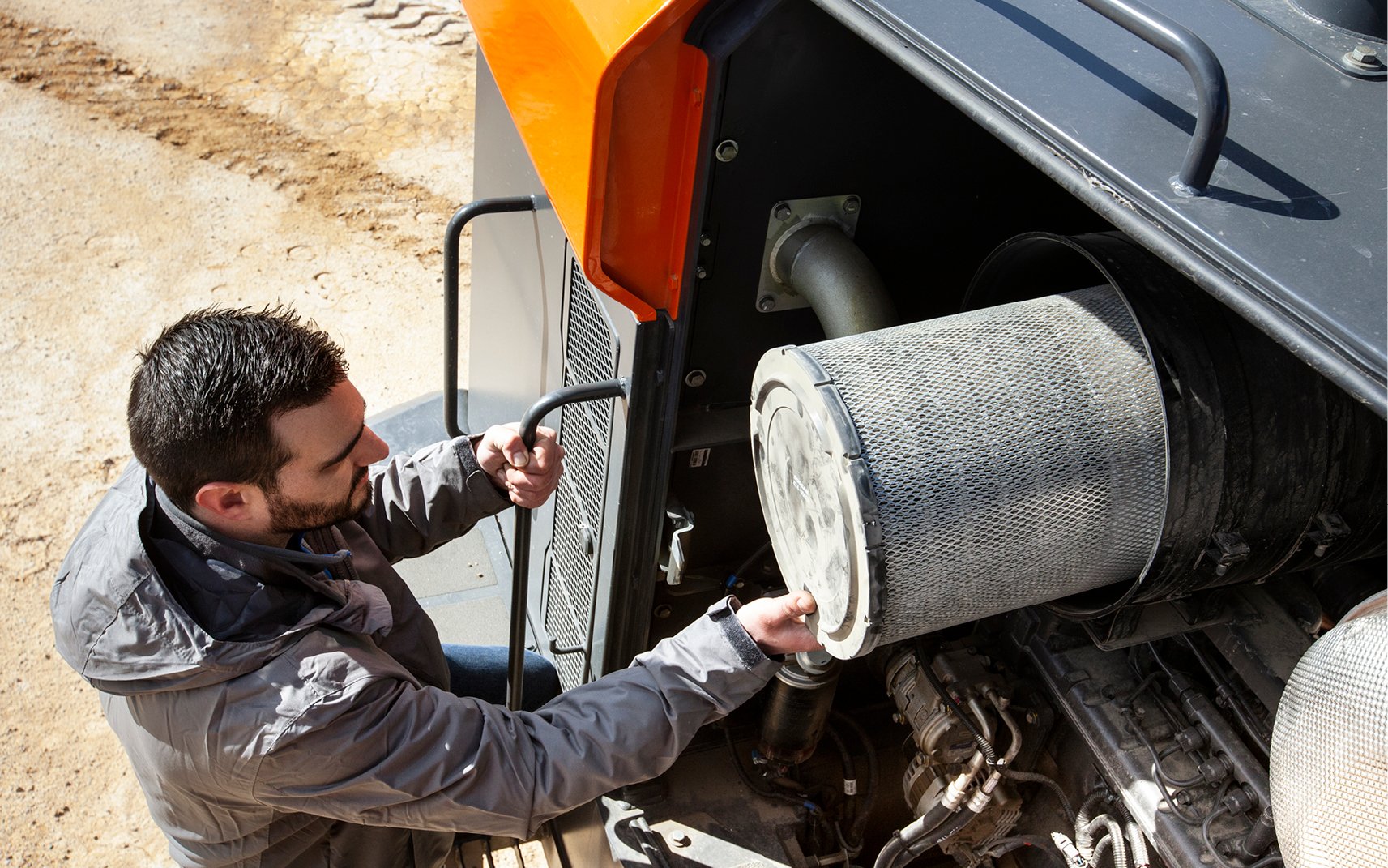 An operator performs preventive maintenance by changing a filter.