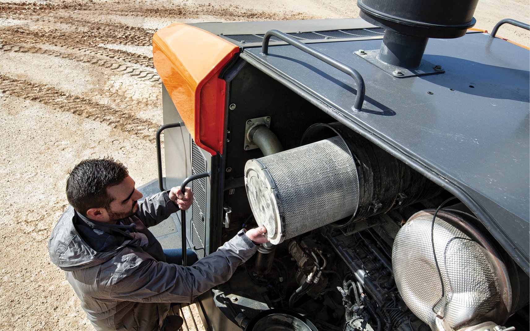 A DEVELON employee replaces an air filter in a crawler excavator.