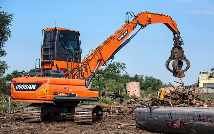 A Doosan DX225MH-5 material handler at APEX Recycling uses a rotating grapple attachment to lift metal.