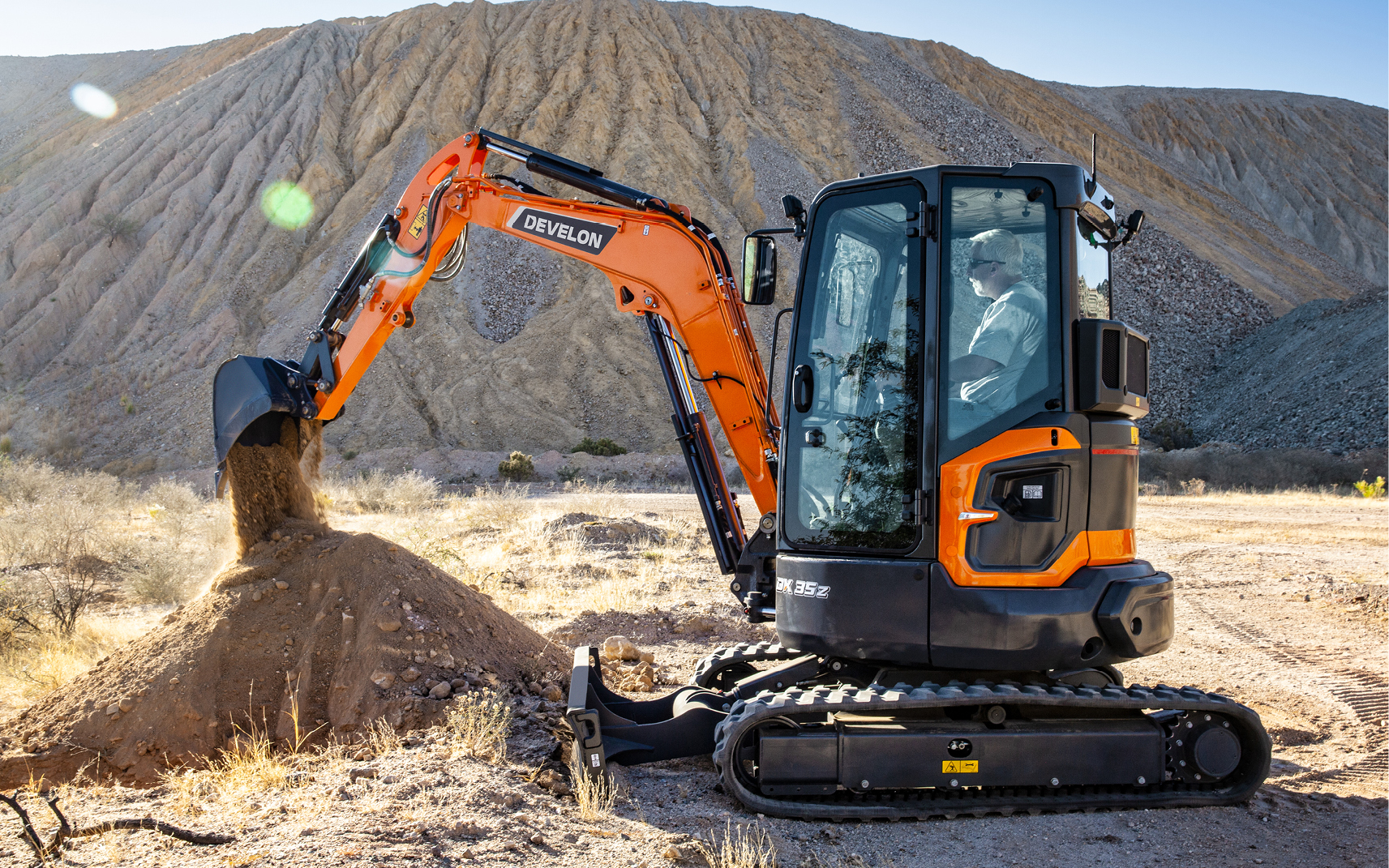 A DX35Z-7 mini excavator operator empties a bucket of dirt in a pile.