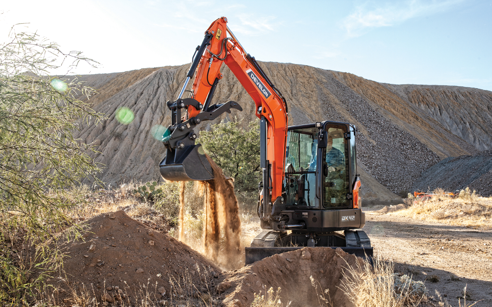 A DX42-7 mini excavator dumping dirt from a bucket.