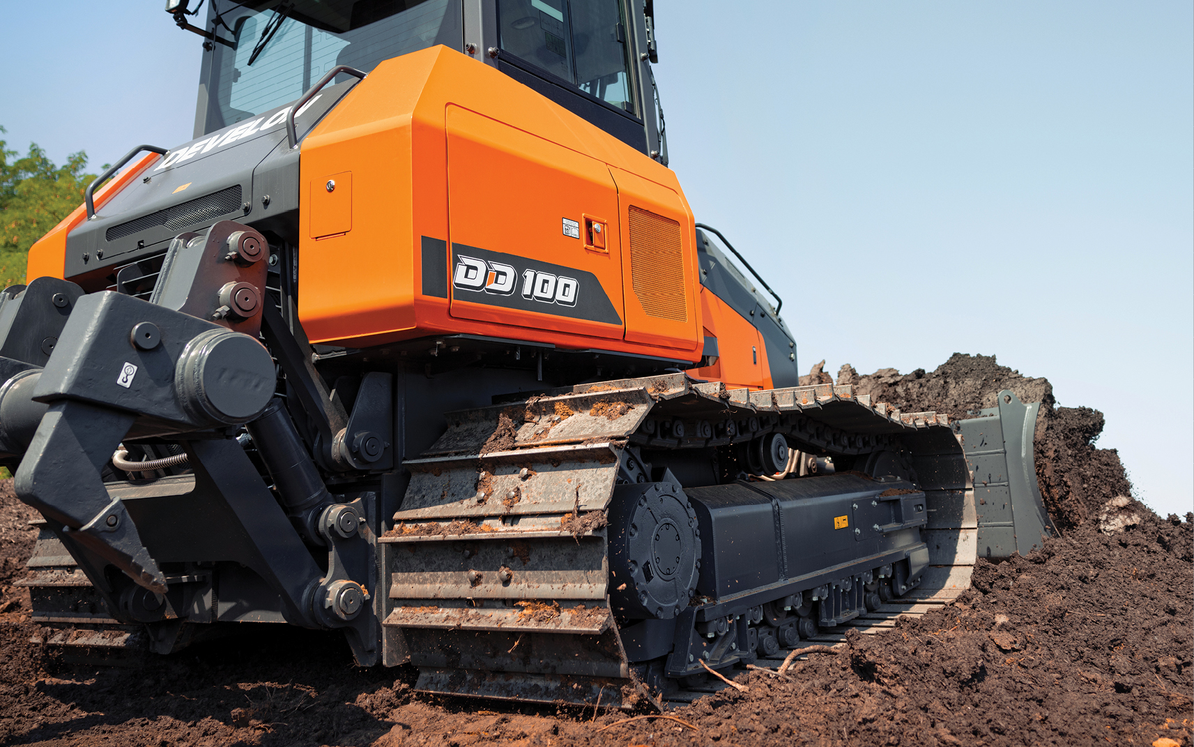 A DEVELON DD100 dozer and its undercarriage pushing dirt on a job site.