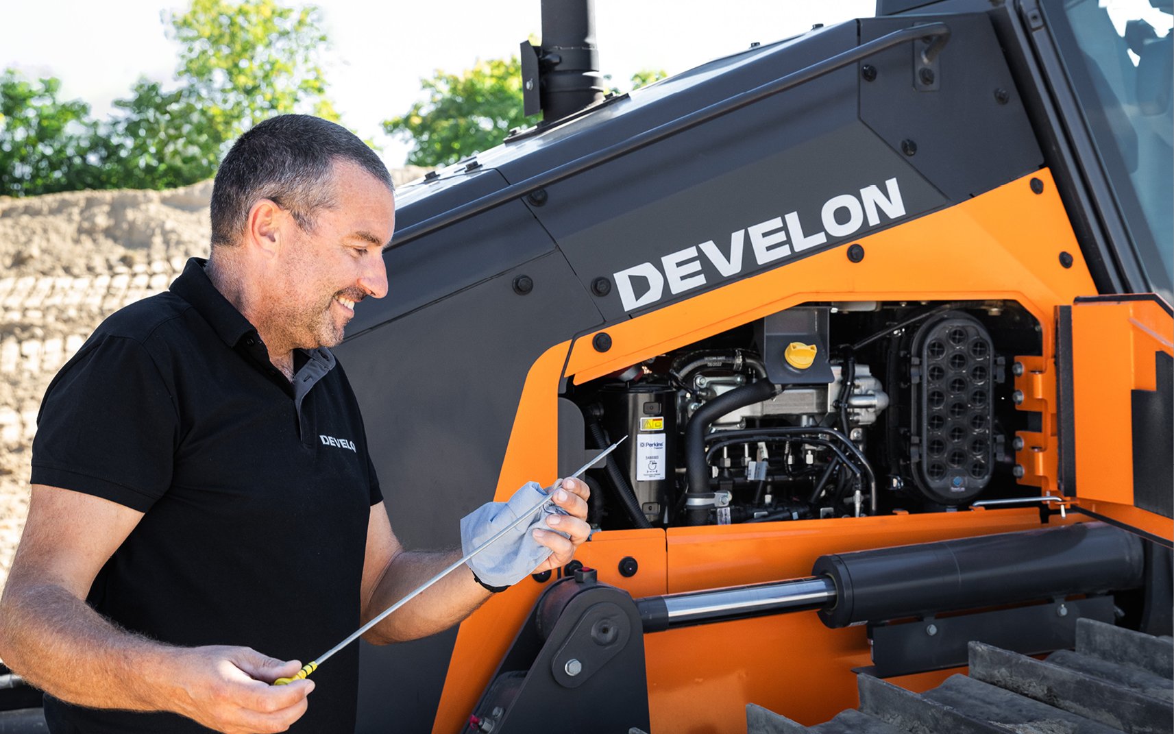 A DEVELON dealer performing routine maintenance on a DEVELON dozer engine.