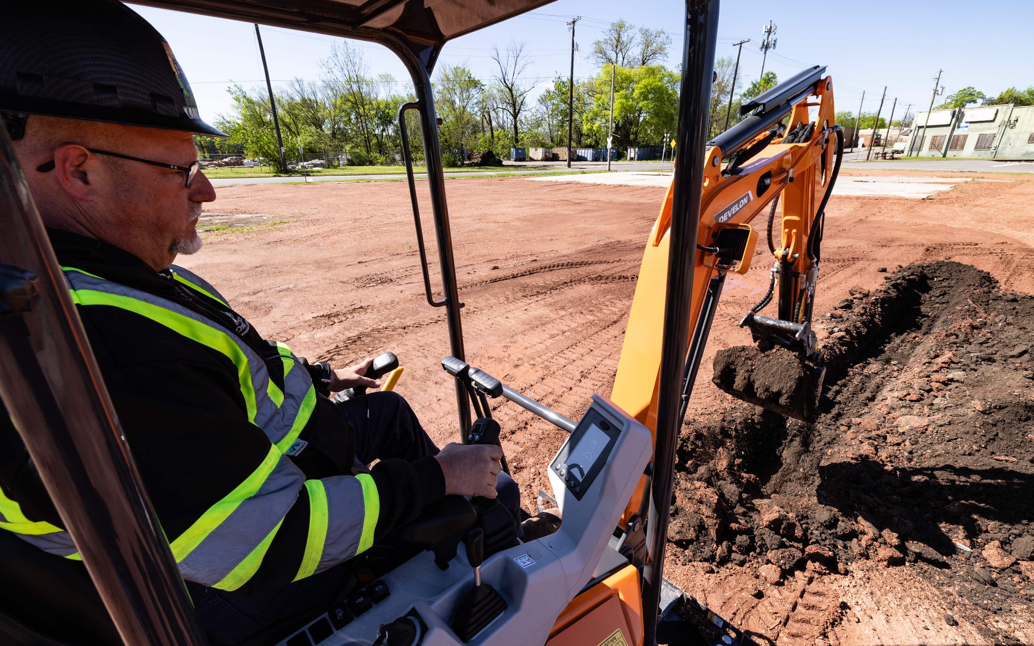 An operator digs a trench with a mini excavator bucket.